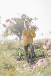 Lächelnde junge Frau mit Spaten im Garten eines Landhauses - KNSF00754