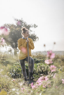 Young woman with spade in cottage garden - KNSF00755