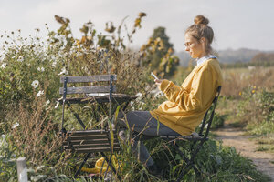 Young woman relaxing in cottage garden - KNSF00764