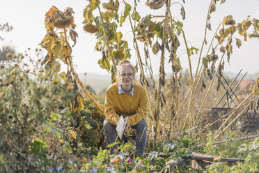 Young woman with book relaxing in cottage garden - KNSF00770