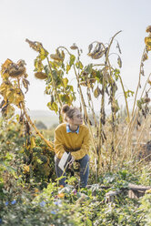 Young woman with book relaxing in cottage garden - KNSF00772