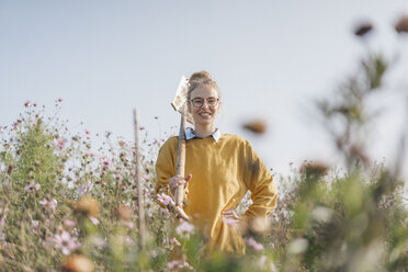 Smiling young woman with spade in cottage garden - KNSF00774