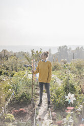 Young woman with spade in cottage garden - KNSF00775