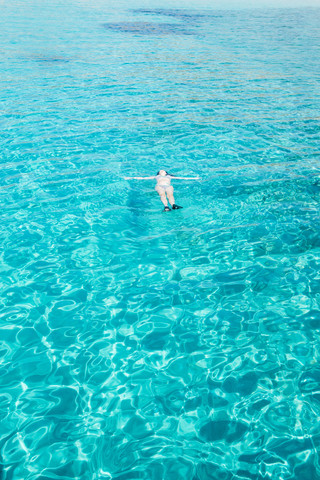 Griechenland, Milos, Frau schwimmt auf dem Wasser, lizenzfreies Stockfoto