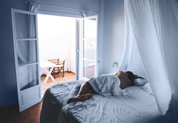 Griechenland, Milos, Frau schlafend in weißen Laken mit offener Balkontür - GEMF01328