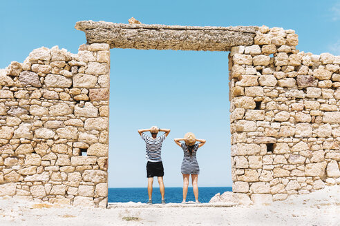 Griechenland, Milos, Firopotamos Beach, Paar steht in Tür in Steinmauer, schaut in die Ferne - GEMF01334