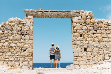 Griechenland, Milos, Firopotamos Beach, Paar steht in Tür in Steinmauer, schaut in die Ferne - GEMF01335