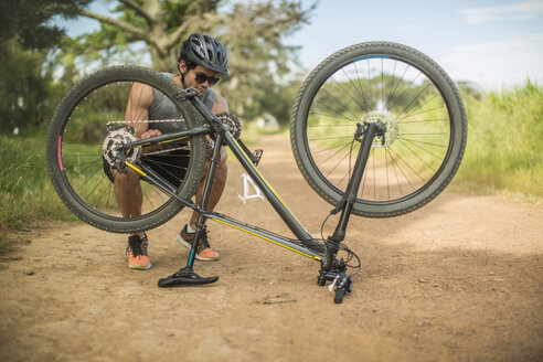 Young man fixing mountain bike on a bike tour - ZEF11875