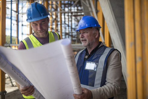 Engineers on construction site discussing blueprint - ZEF11885