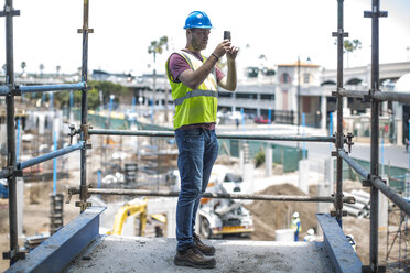 Bauarbeiter auf einer Baustelle, der mit seinem Smartphone Fotos macht - ZEF11890