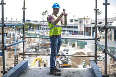 Construction worker on construction site taking pictures with smart phone - ZEF11890