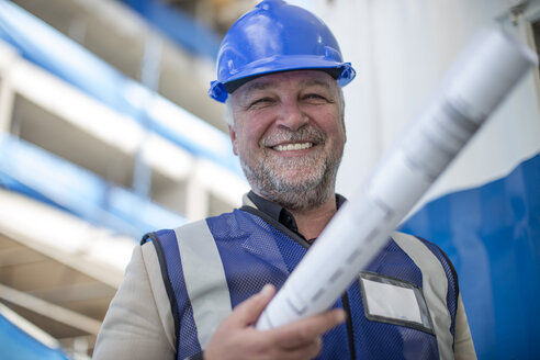 Engineer on construction site holding blueprint - ZEF11895