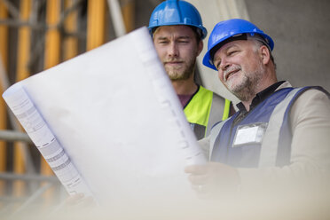 Engineers on construction site discussing blueprint - ZEF11896