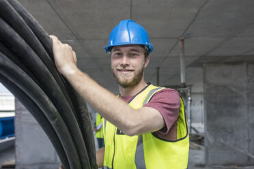 Bauarbeiter auf der Baustelle, der Kabel trägt - ZEF11898