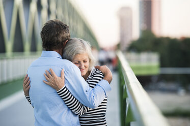 Senior couple embracing on a bridge - HAPF01252