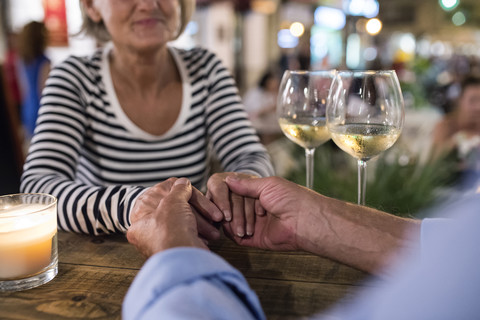 Älteres Paar Hand in Hand an einer Bar im Freien, lizenzfreies Stockfoto