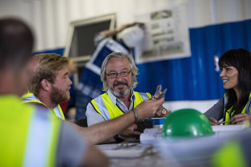 Construction worker and engineer discussing project in site office - ZEF11936