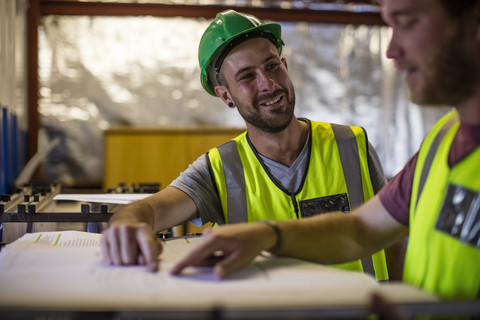 Construction worker and engineer discussing project in site office stock photo