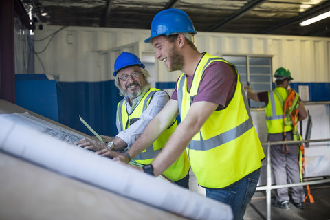 Construction worker and engineer discussing project in site office stock photo