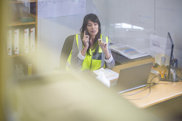 Female construction engineer making a call in site office - ZEF11952