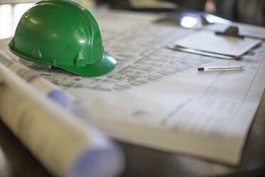 Construction helmet on blueprints in site office - ZEF11954