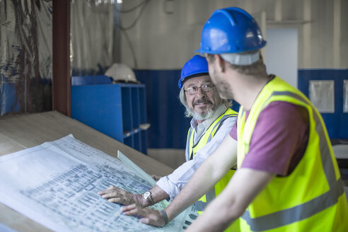 Construction worker and engineer discussing project in site office - ZEF11958