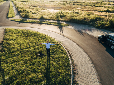 Businessman standing in roundabout spreading out his arms stock photo