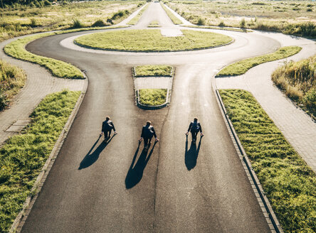 Three businessmen starting race at roundabout - KNSF00795