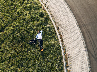 Businessman lying on traffic island in roundabout - KNSF00803