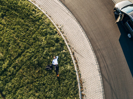 Businessman lying on traffic island in roundabout - KNSF00804