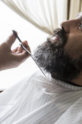Barbier schneidet den Bart eines Mannes - ABZF01652