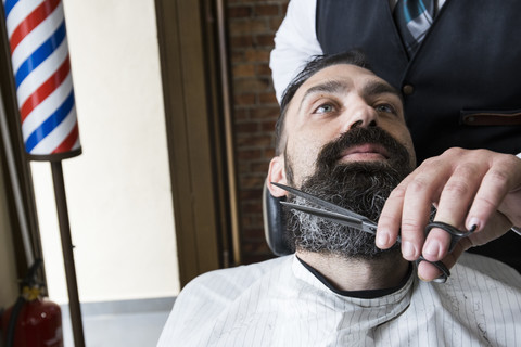 Barbier schneidet den Bart eines Mannes, lizenzfreies Stockfoto