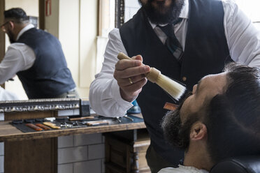 Barbier reinigt den Bart eines Mannes mit einer Bürste - ABZF01662
