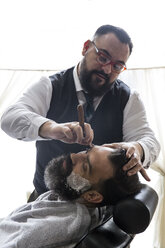 Barbier rasiert einen Mann mit einem Rasiermesser - ABZF01671