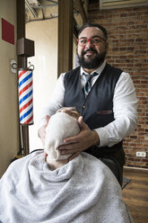 Friseur, der einem Mann nach der Rasur ein Handtuch auf den Bart legt - ABZF01673