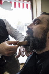 Barbier bürstet den Bart eines Mannes mit einer Haarbürste - ABZF01679