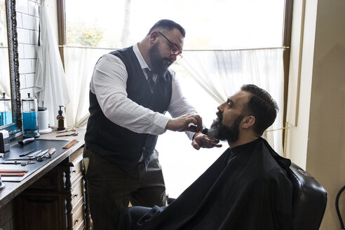 Barbier bürstet den Bart eines Mannes mit einer Haarbürste - ABZF01680