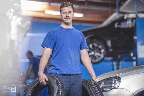Mechaniker mit Reifen in der Werkstatt, lizenzfreies Stockfoto
