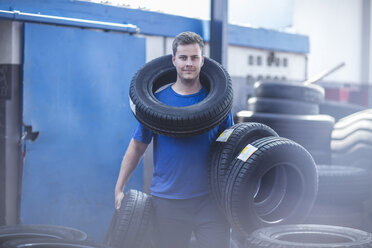 Mechanic holding batch of tyres - ZEF11996