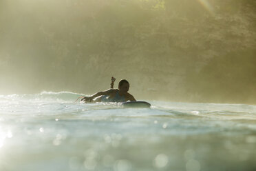 Indonesien, Bali, Frau auf Surfbrett im Meer liegend - KNTF00593