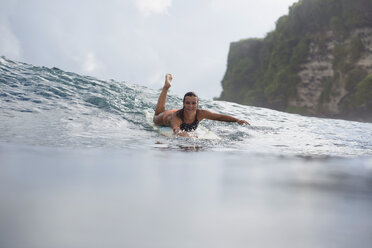 Indonesia, Bali, woman lying on surfboard in the sea - KNTF00599