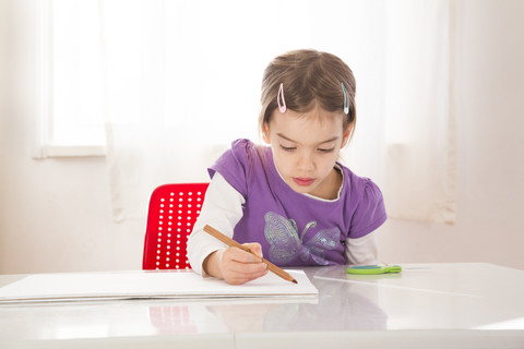 Kleines Mädchen macht eine Zeichnung auf einem Blatt Papier, lizenzfreies Stockfoto