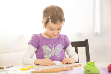 Littel girl tinkering at home, folding paper - LVF05736
