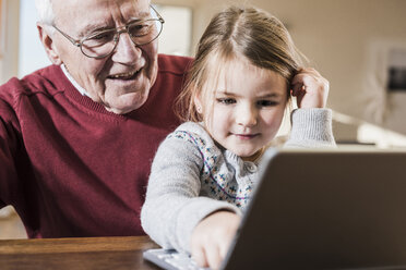 Großvater und Enkelin benutzen gemeinsam einen Laptop - UUF09538