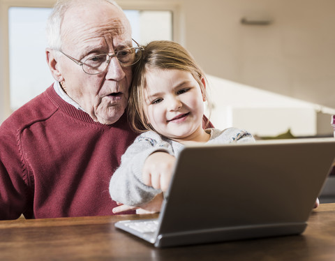 Großvater und Enkelin benutzen gemeinsam einen Laptop, lizenzfreies Stockfoto