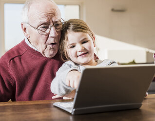 Großvater und Enkelin benutzen gemeinsam einen Laptop - UUF09539