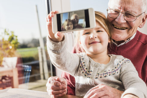 Grandfather and granddaughter taking selfies with a smart phone - UUF09546