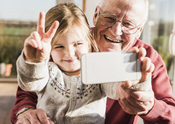 Grandfather and granddaughter taking selfies with a smart phone - UUF09547