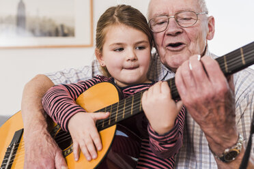 Grandfather and granddaughter playing together guitar - UUF09553