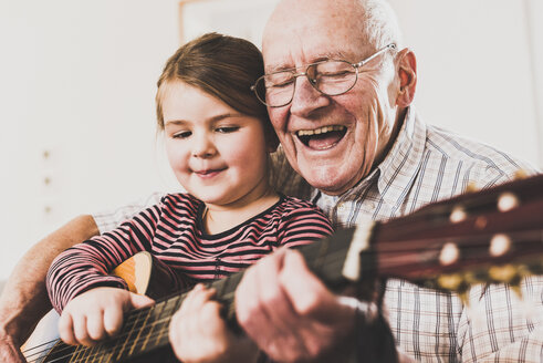 Grandfather and granddaughter playing together guitar - UUF09554